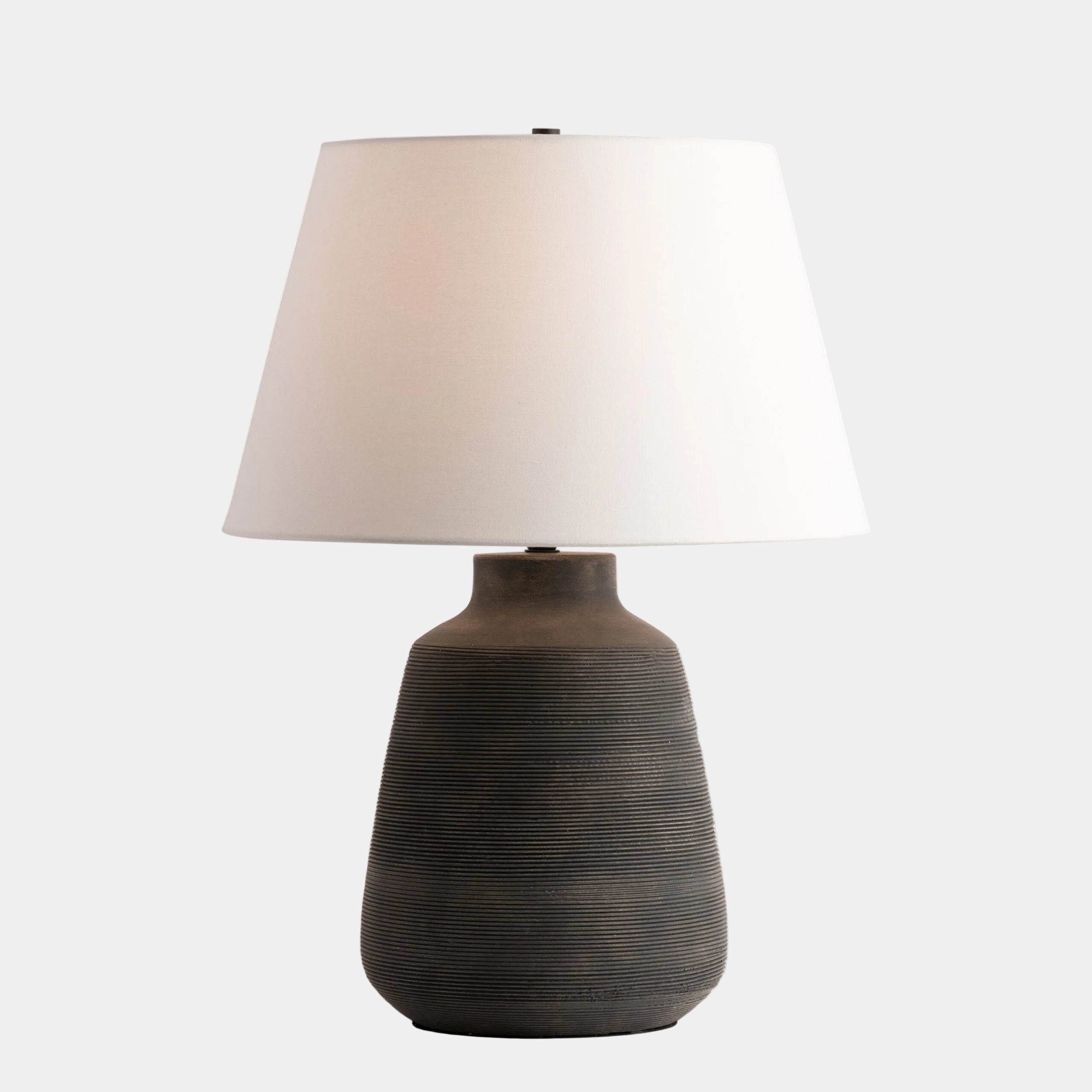 Table lamp with a textured brown base and white shade on a white background