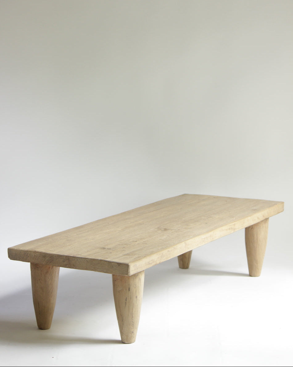 A low, rectangular, elm wood coffee table with visible grain and natural color, placed against a neutral background.