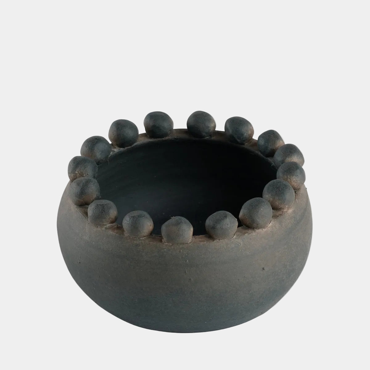 Black ceramic bowl with raised circular rim on a white background