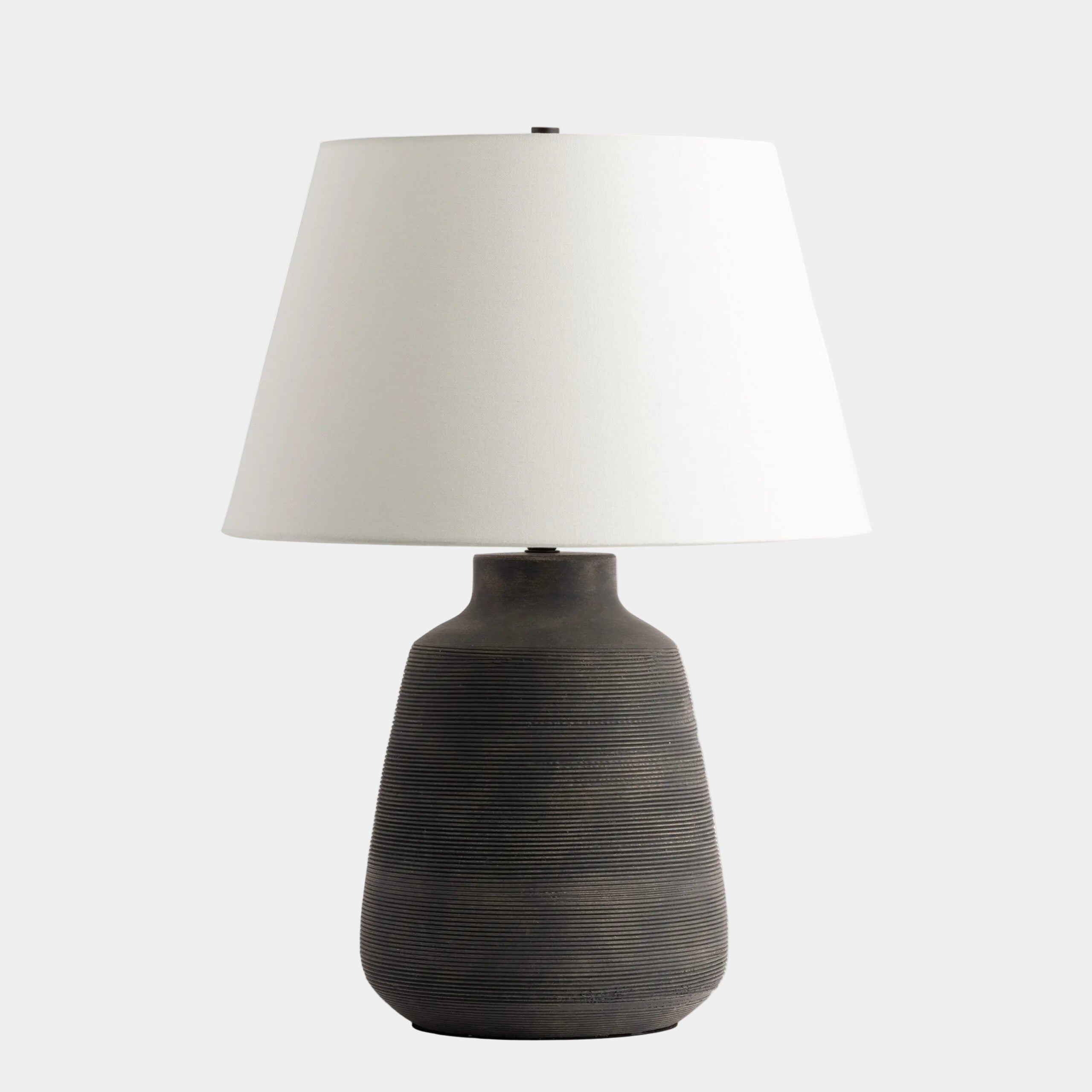 Table lamp with a textured black base and white shade on a white background