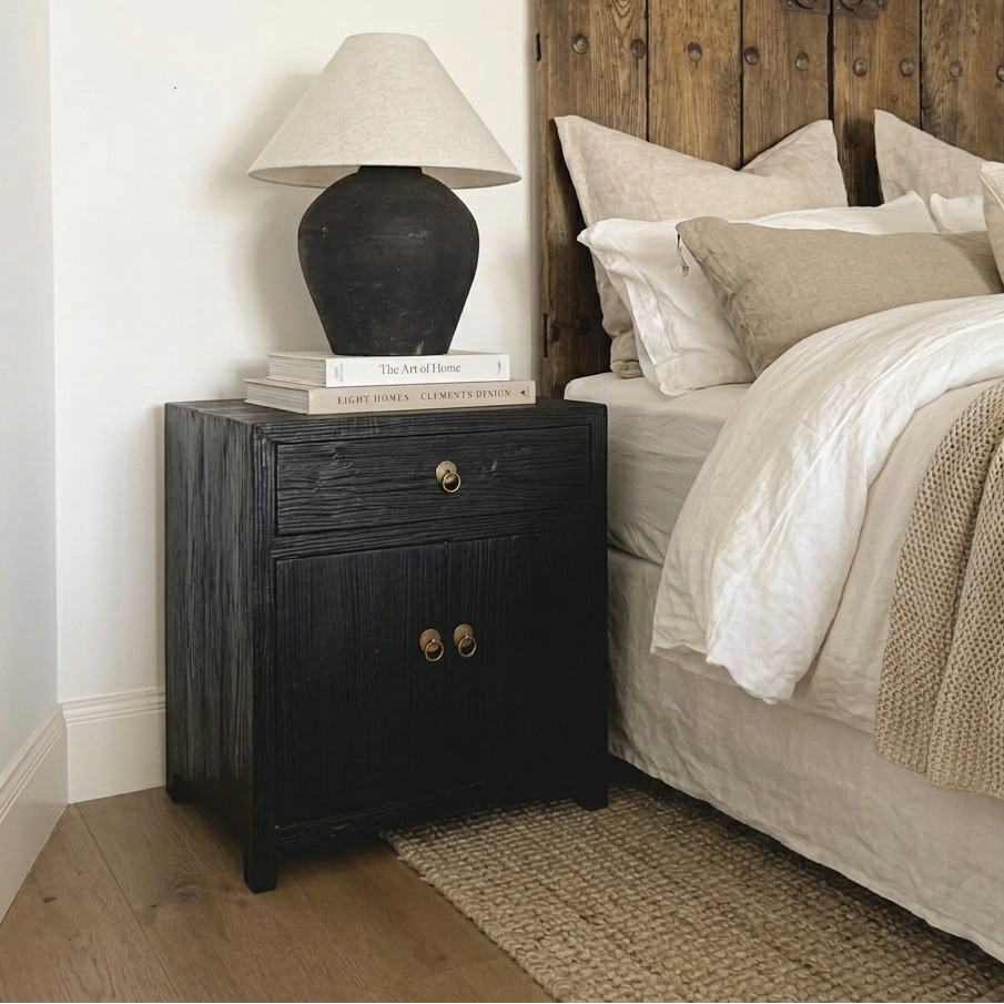 Bedroom with wooden headboard, black nightstand, and lamp.