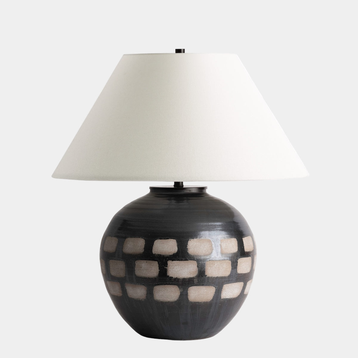 Table lamp with a checkered design base and white shade on a white background