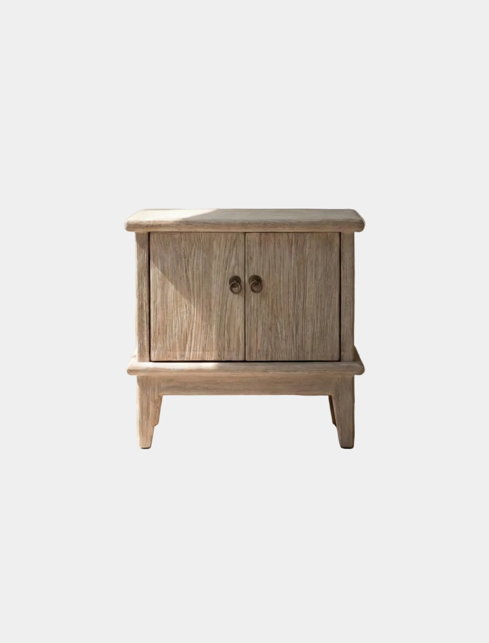 Wooden nightstand with two doors on a light wooden floor.